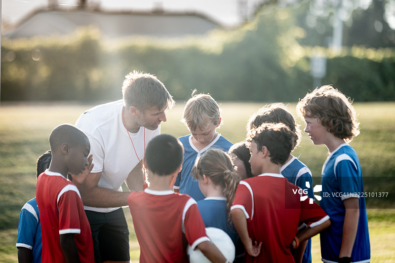 教练在阳光明媚的日子里与青少年足球队交谈图片素材