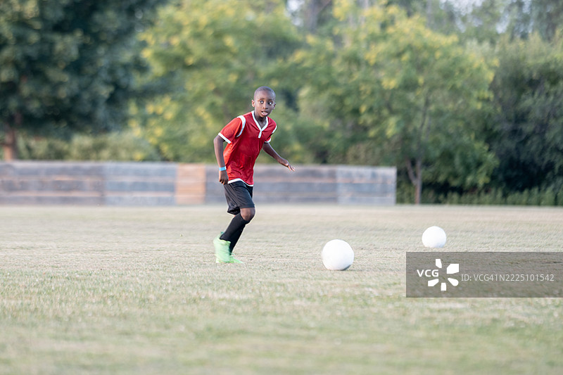 年轻足球运动员在阳光明媚的日子里在球场上练习图片素材