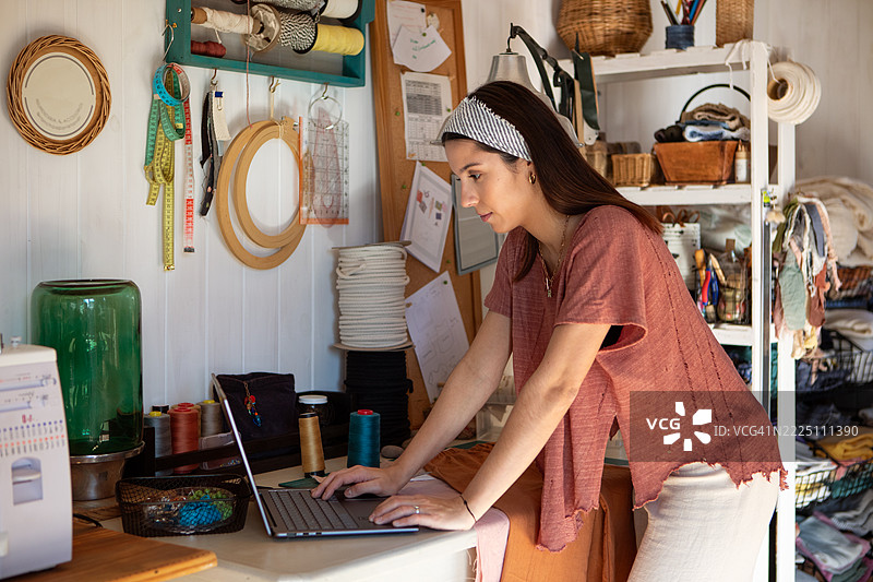 年轻女性纺织企业家在她的创意工作室里图片素材