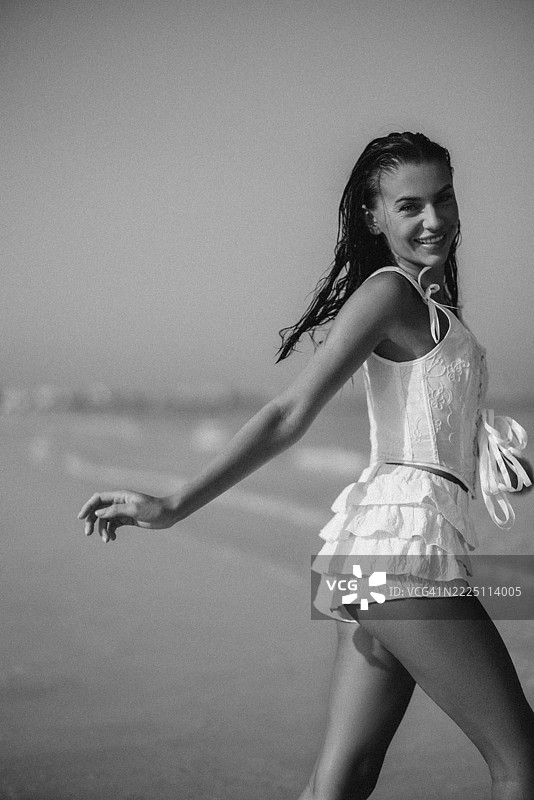 微笑的女性在海滩上享受阳光，穿着白色衣服图片素材