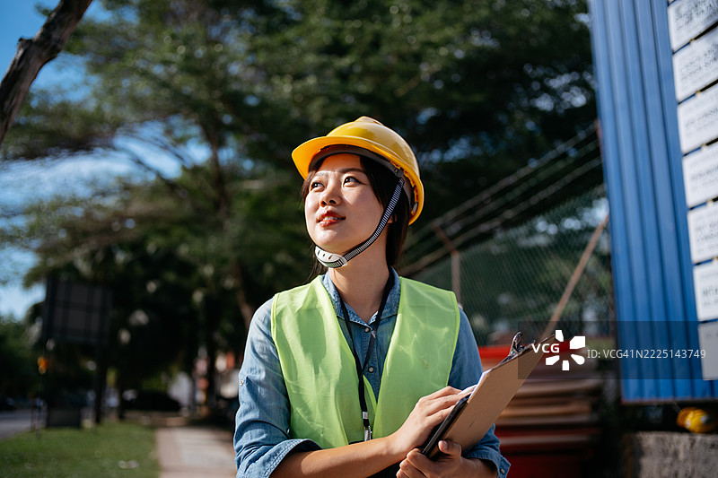 户外建筑工地上的亚洲女性工程师手持夹板图片素材