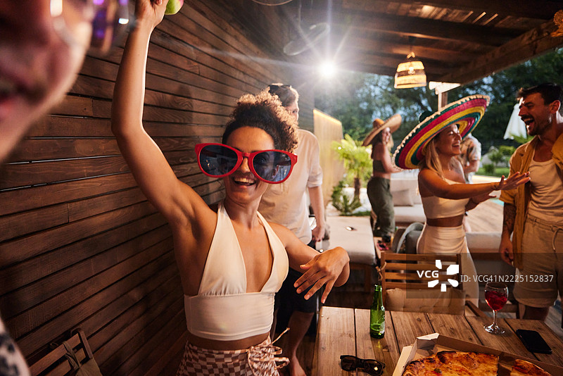 快乐的女人在露台派对上与朋友们尽情玩乐。图片素材