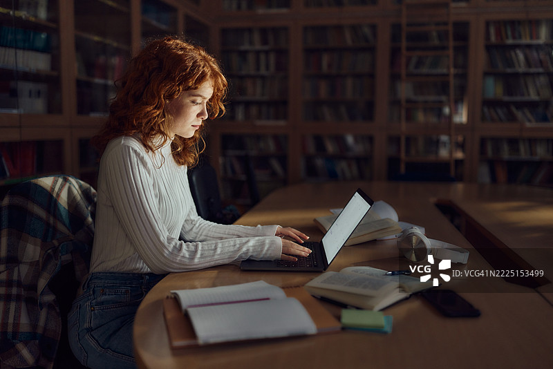女学生在图书馆使用笔记本电脑进行在线学习。图片素材