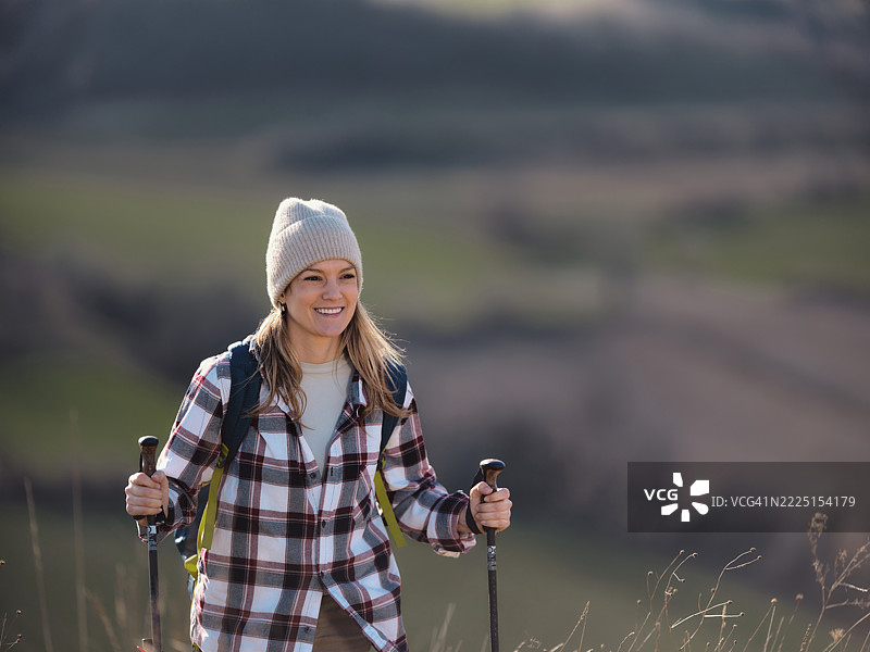快乐的女人在秋天的草地上徒步旅行。图片素材