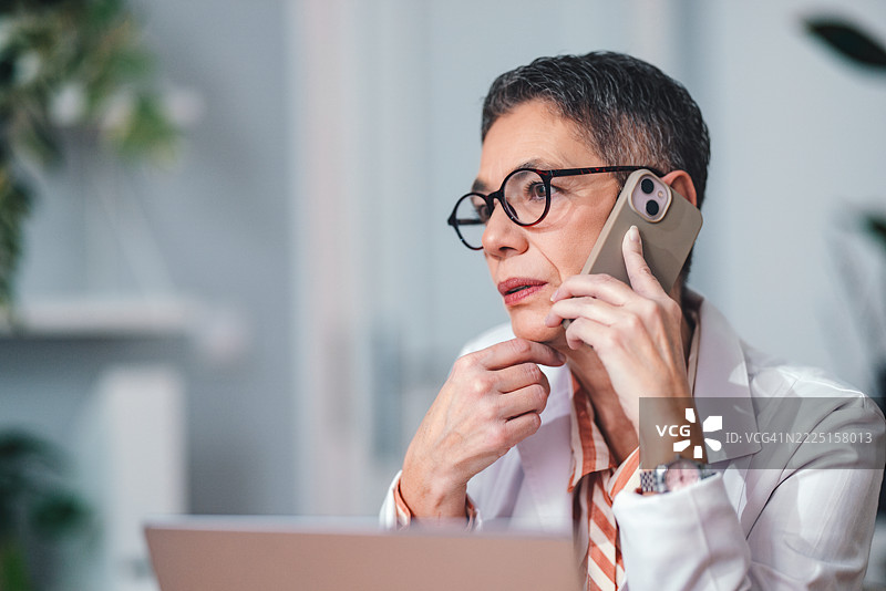 专业女性医生在办公室工作时通过电话讨论图片素材