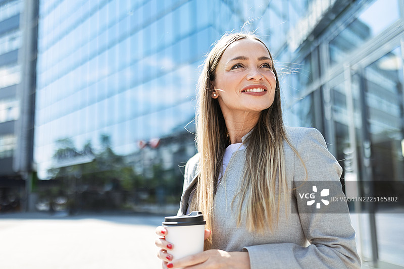 手握咖啡的职业女性在户外站立图片素材