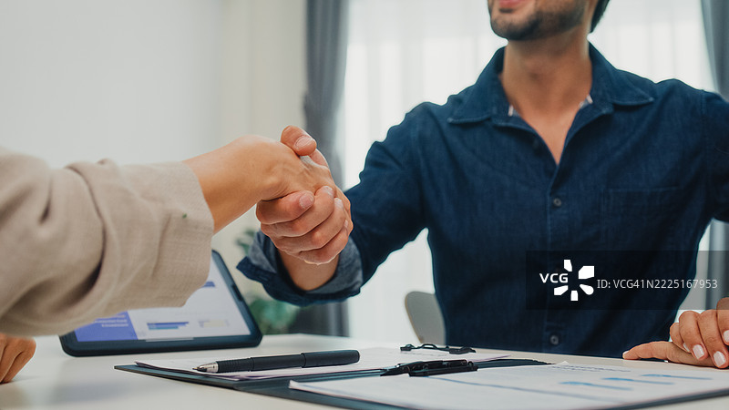 年轻夫妇在家客厅与财务顾问签署财务协议的特写镜头。财务规划与生活方式概念。图片素材