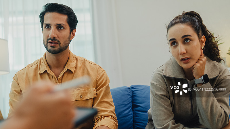 年轻夫妇在家中的客厅沙发上与心理健康专业人士进行严肃讨论，参加婚姻咨询会议。治疗会议心理健康概念。图片素材