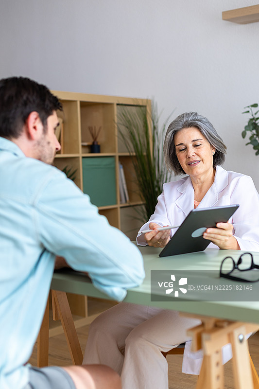女医生在医疗咨询中向患者展示平板上的信息图片素材