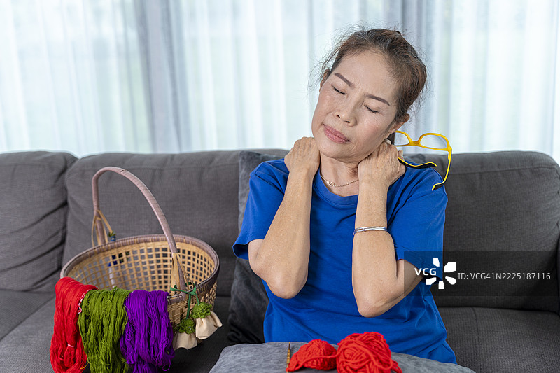 一位因爱好而感到颈部疼痛和肩部僵硬的年长亚洲女性图片素材