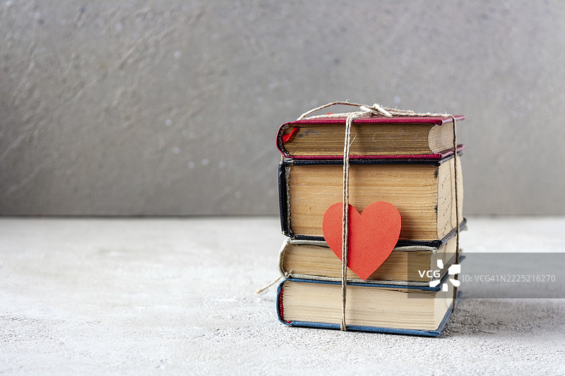 用麻绳绑着的旧书和红色纸心，留白空间图片素材