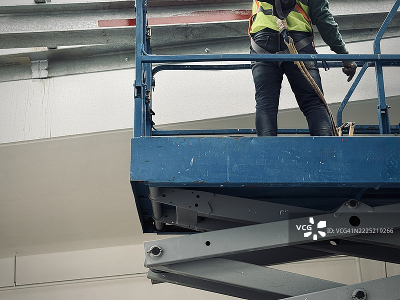 穿着安全带的升降机操作工站在剪刀升降平台上图片素材