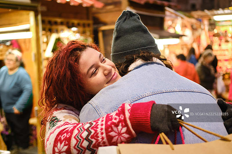 年轻情侣在巴塞罗那的圣诞市场拥抱图片素材