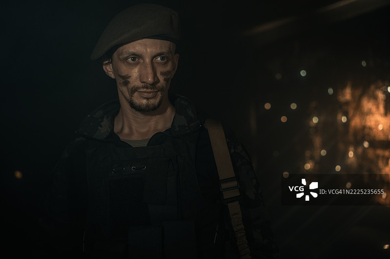 身着迷彩服、脸上涂有战斗彩绘的士兵肖像，背景气氛戏剧化图片素材