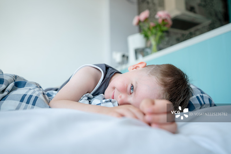 年轻男孩在明亮舒适的室内环境中放松躺在床上图片素材