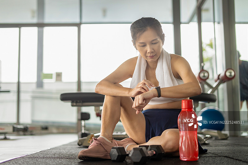 女性运动员在健身房查看智能手表图片素材