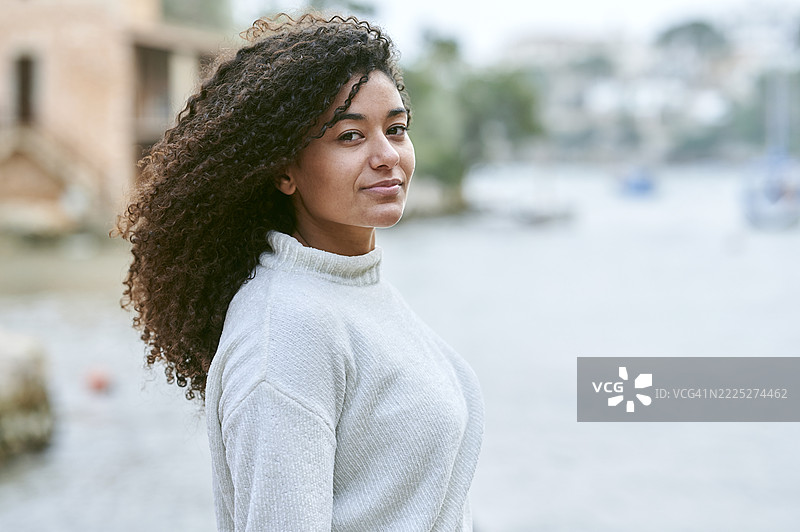 一位卷发女性的肖像，背景是阴天的海洋。图片素材