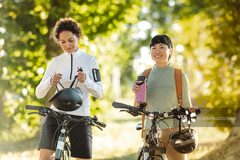 两个朋友在阳光明媚的森林中享受骑行之旅图片素材