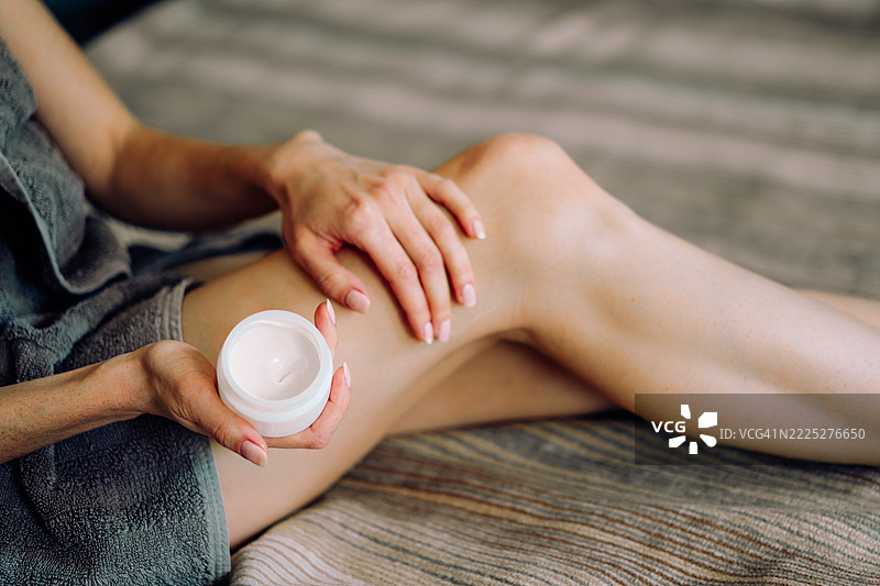 女性在腿部涂抹护肤乳液，以获得滋润光滑的肌肤图片素材