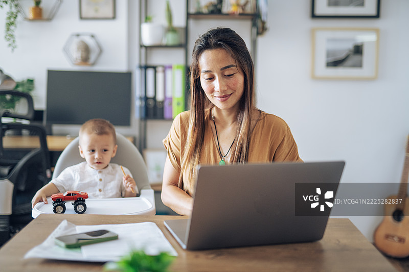 单身亚洲母亲在工作和照顾小孩之间忙碌。图片素材