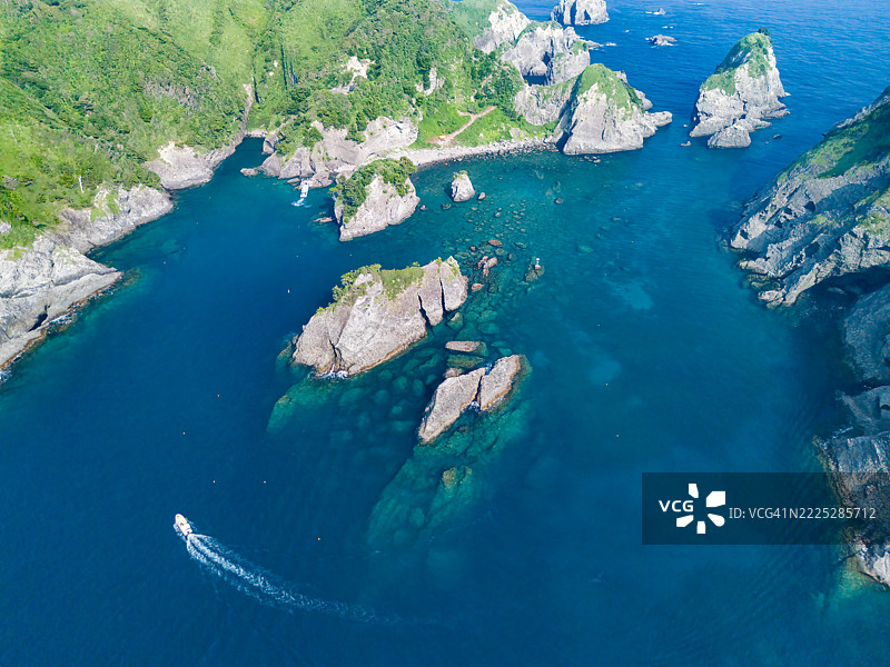 许多游泳者在从上方看到的Hirizo海滩游泳。海滩外有一个大型的Ohnejima岛。一艘从港口运输他们的渡轮渔船也在运营。图片素材