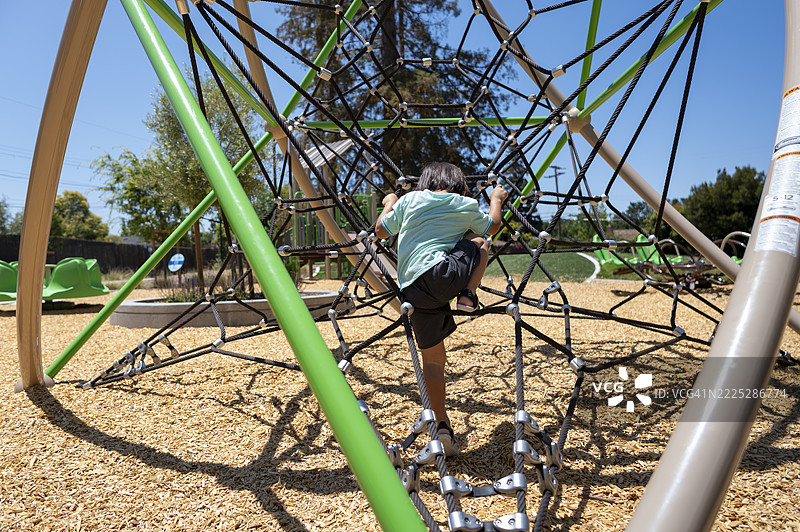 年轻的日本男孩在晴朗的夏空下独自在攀爬网玩耍图片素材