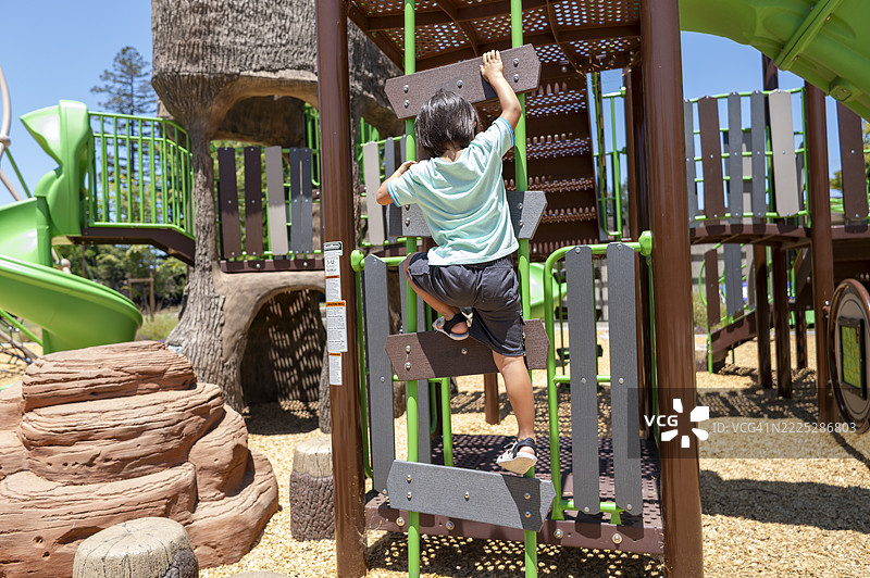 日本孩子在阳光明媚的夏日攀爬自然岩石状的游乐设施图片素材