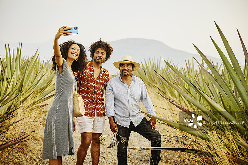 中景拍摄的情侣与龙舌兰农场主在旅游中合影自拍图片素材