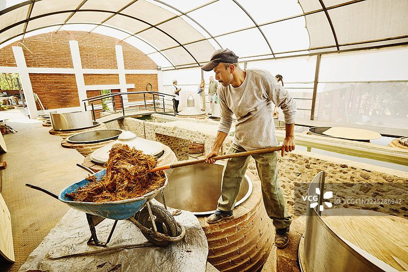 工人在酿酒厂将捣碎的龙舌兰加入发酵罐的广角镜头图片素材