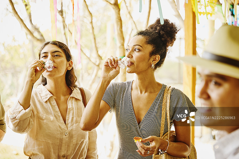 中景好奇的女性在蒸馏厂参观时品尝梅斯卡尔酒图片素材