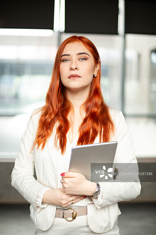 自信的女商人在现代办公室中手持数字平板电脑图片素材