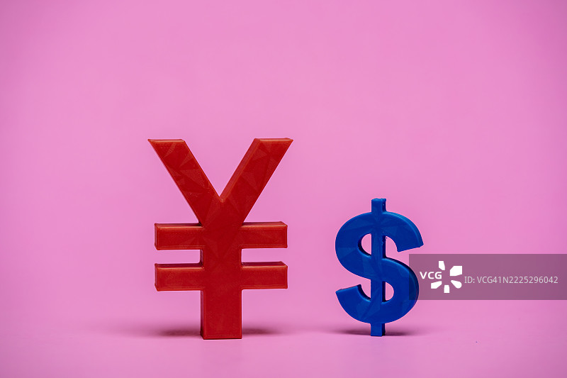 红色日元符号和蓝色美元符号站在粉色背景上图片素材
