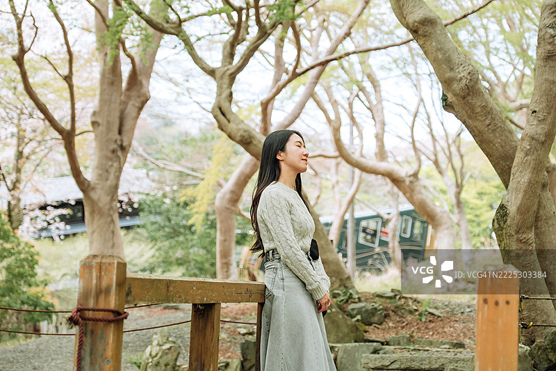 放松的年轻亚洲女性在日本的森林中散步，享受大自然。享受无忧无虑的时刻。与自然的自由连接。图片素材