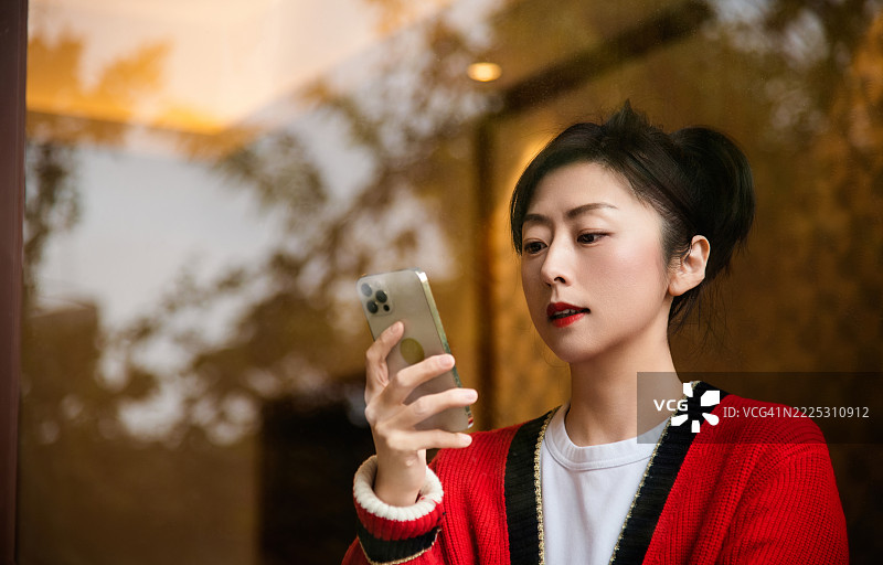 女人在窗后使用手机图片素材