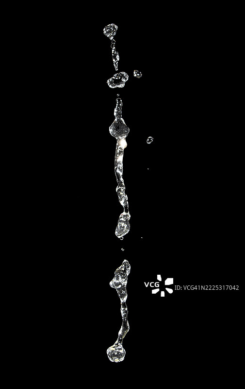 黑色背景上悬浮的透明水滴。图片素材