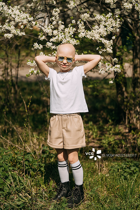 戴着太阳镜的光头孩子享受春天的花朵图片素材