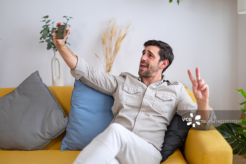 年轻男子在家沙发上放松时自拍图片素材