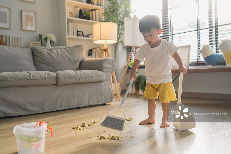 可爱的小男孩在帮妈妈做家务，用扫帚扫地。小孩通过家庭清洁任务学习责任感，参与有趣且有帮助的家务活动。图片素材