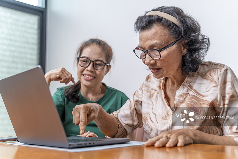 快乐的亚洲老年女性使用笔记本电脑图片素材