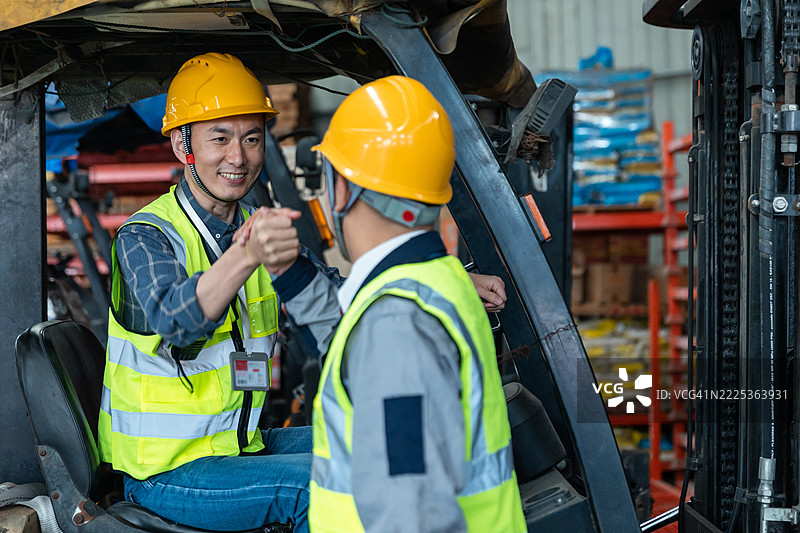 两位亚洲货运场经理在仓库里用叉车交流图片素材