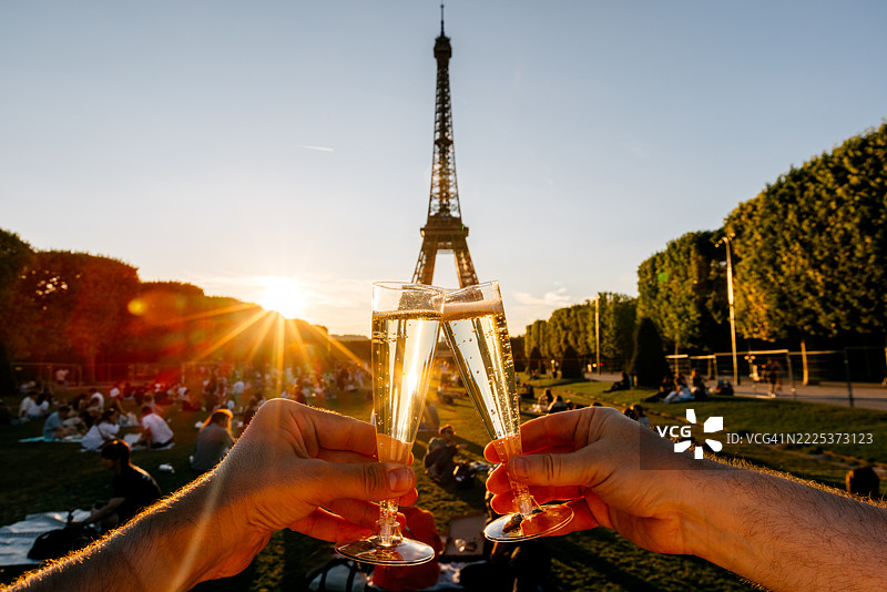 两个人在巴黎的埃菲尔铁塔前的香榭丽舍公园举杯庆祝，夕阳下的个人视角。图片素材