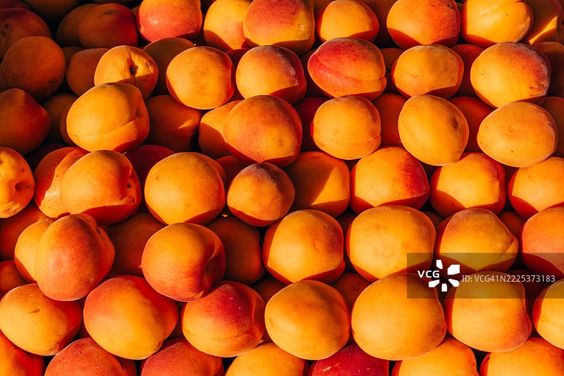 农贸市场上出售的新鲜多汁的五彩杏子堆。图片素材