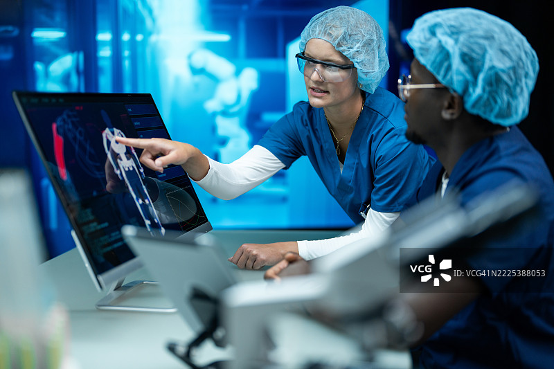 多元化的科学家在未来感触控电脑上审查全身扫描结果图片素材