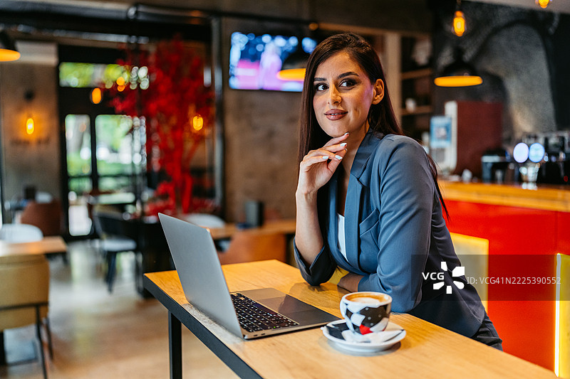 年轻女商人在咖啡店里一边喝咖啡一边使用笔记本电脑工作图片素材