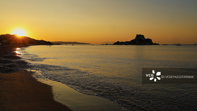 宁静的日落,远眺岛屿和金色天空,阿吉奥斯·斯特法诺斯海滩,阿吉奥斯·斯特法诺斯大教堂,教堂,卡斯特里岛,科斯岛,多德卡尼斯群岛,希腊图片素材