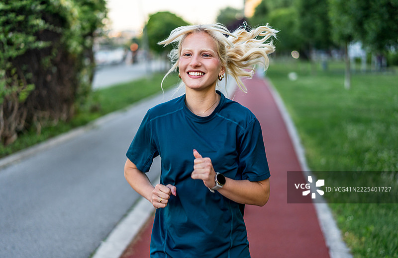 年轻女性在跑道上奔跑，享受她的锻炼时光图片素材
