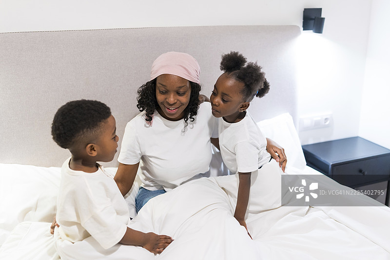 妈妈在接受化疗，她微笑着和孩子们玩耍，展现出坚韧不拔的精神，并在生病期间维系着家庭纽带。图片素材