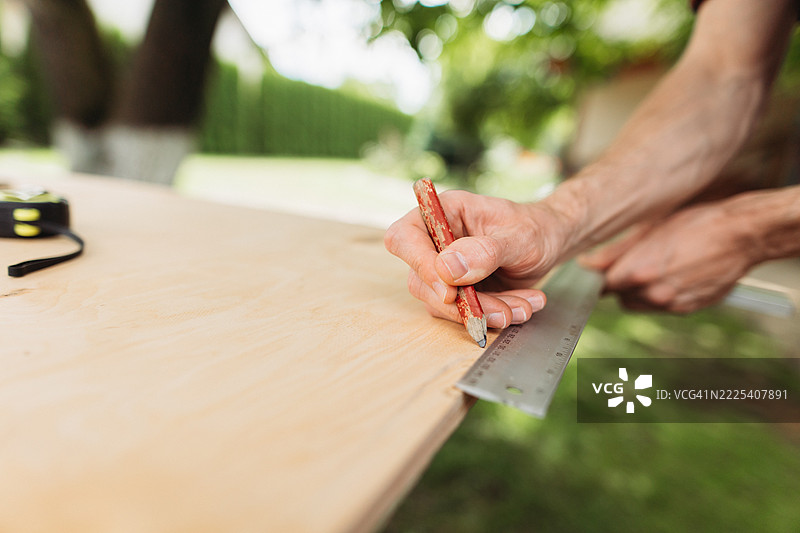 一个无法辨认的男子在胶合板上绘制切割图案图片素材