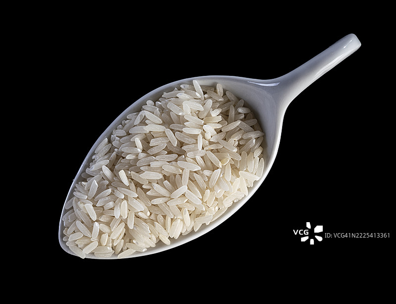 黑色背景上的瓷勺与生长米。图片素材