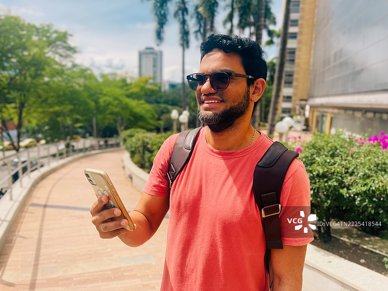 男子在街上走路时使用智能手机图片素材